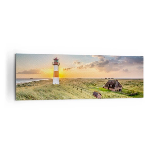 Impression sur toile - Image sur toile - Un phare avec des prairies et des maisons au soleil en arrière-plan - 160x50cm - Entre les vagues - Décoration murale moderne pour le salon et la chambre ARTTOR