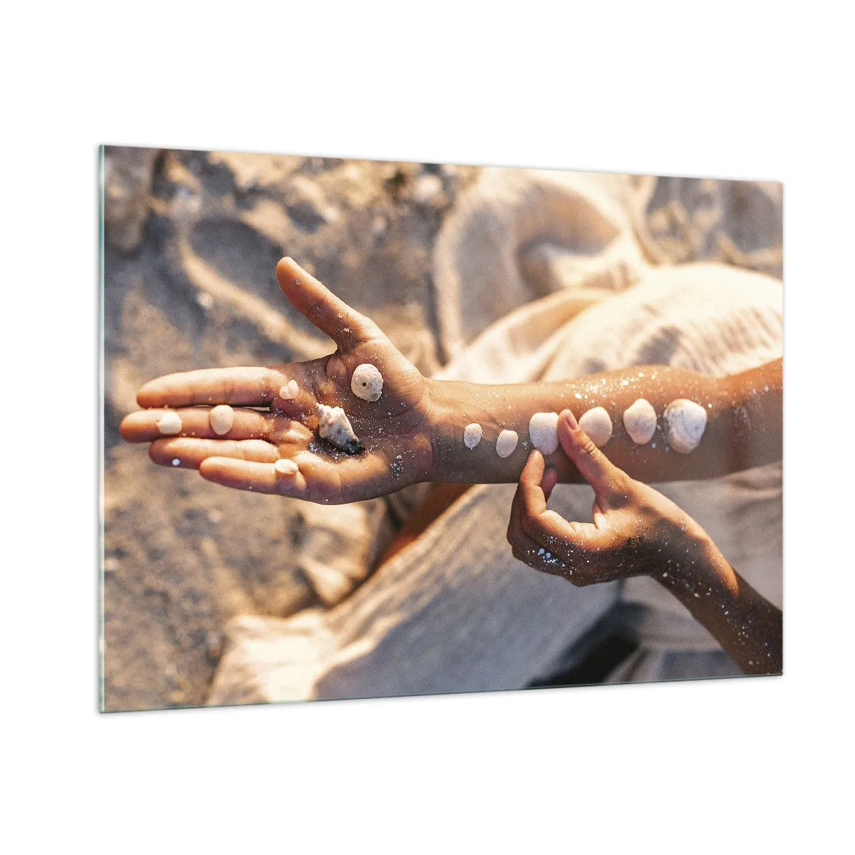Impression sur verre - Image sur verre - Mains d'enfant avec des coquillages sur un fond de sable et de tissu - 100x70cm - La beauté à portée de main - Décoration murale moderne pour le salon et la chambre ARTTOR
