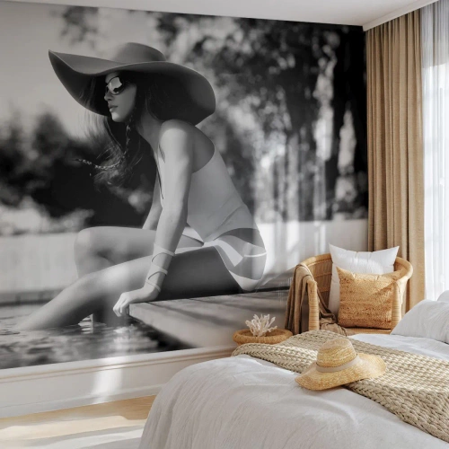 Papier Peint Photo Premium Sand - Une femme portant un chapeau assise au bord de la piscine - 100x70cm - Rêve d'été - Décoration murale moderne pour le salon et la chambre ARTTOR
