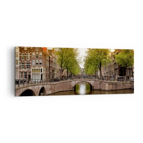 Impression sur toile - Image sur toile - Un canal à Amsterdam entouré d'immeubles historiques - 140x50cm - En bateau ou à vélo ? - Décoration murale moderne pour le salon et la chambre ARTTOR