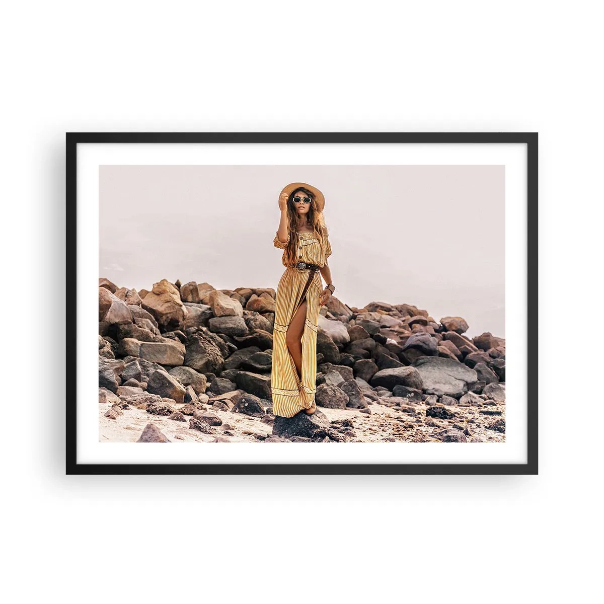 Affiche dans un cadre noir - Poster - Une femme au style bohème sur fond de plage rocheuse - 70x50cm - La magie des pierres - Décoration murale moderne pour le salon et la chambre ARTTOR